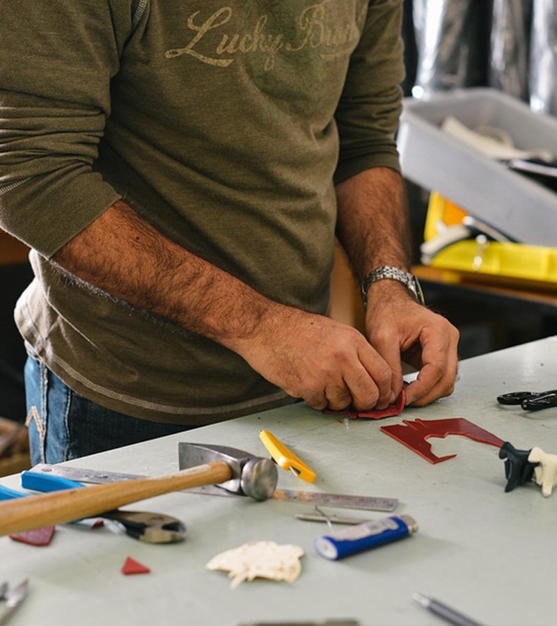 Craftsperson cutting material at a workbench